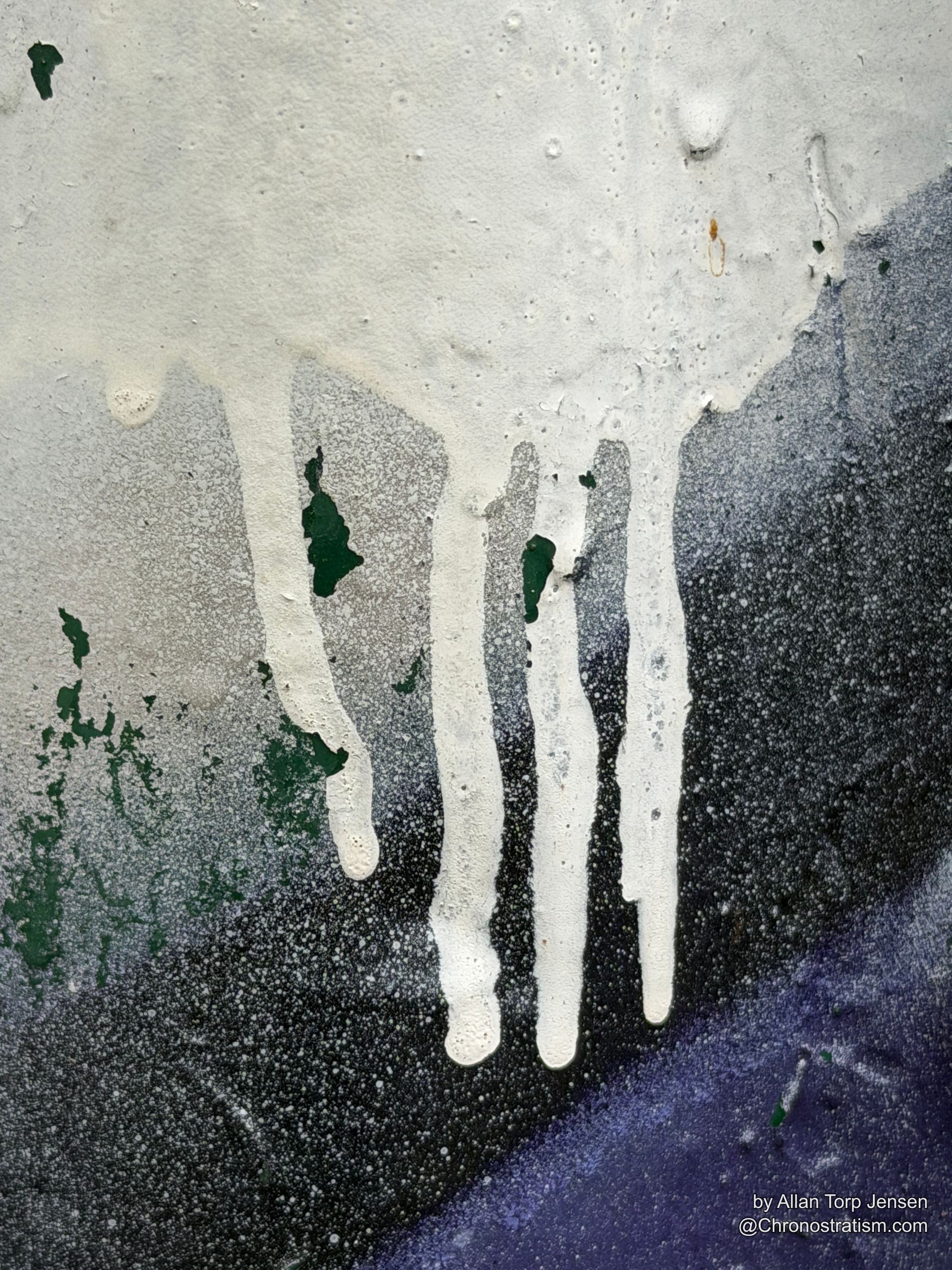 Abstract white and purple spray paint drips bleed across a dark painted surface.