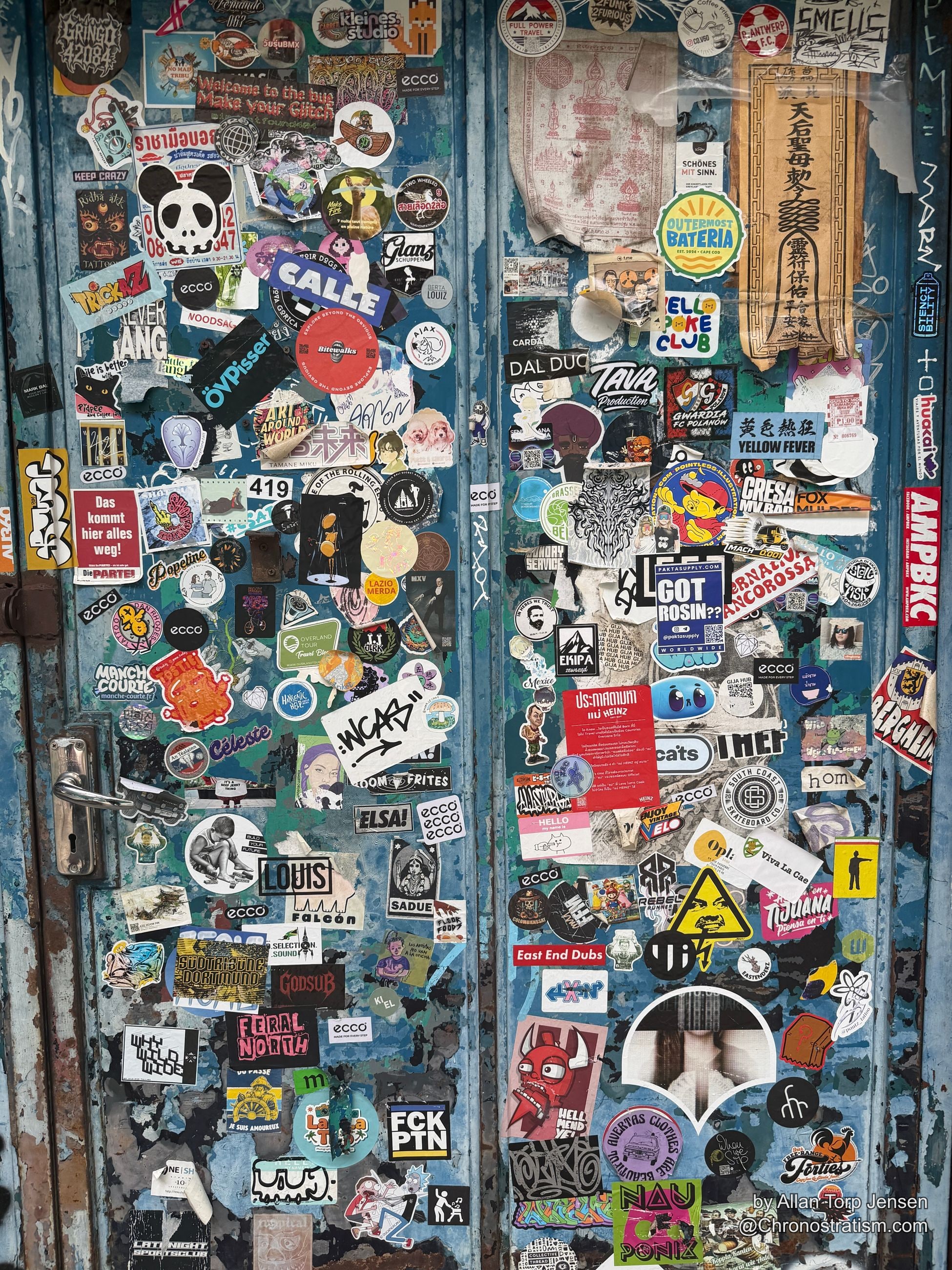 Close crop of the same sticker-covered door, crew tags and character stickers overlapping.