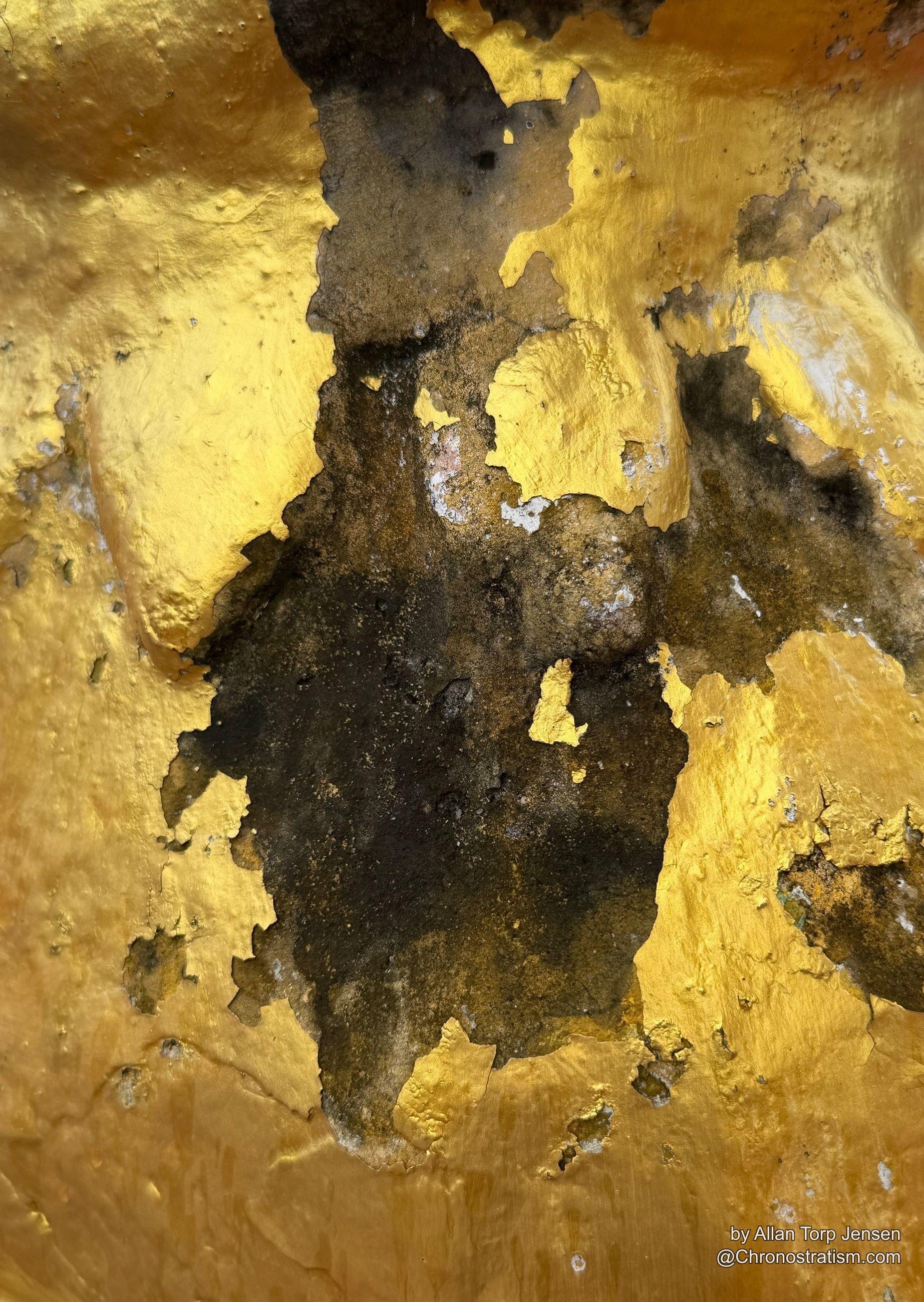 Gold leaf flakes away in ridged sheets, black grime packed into the seams.