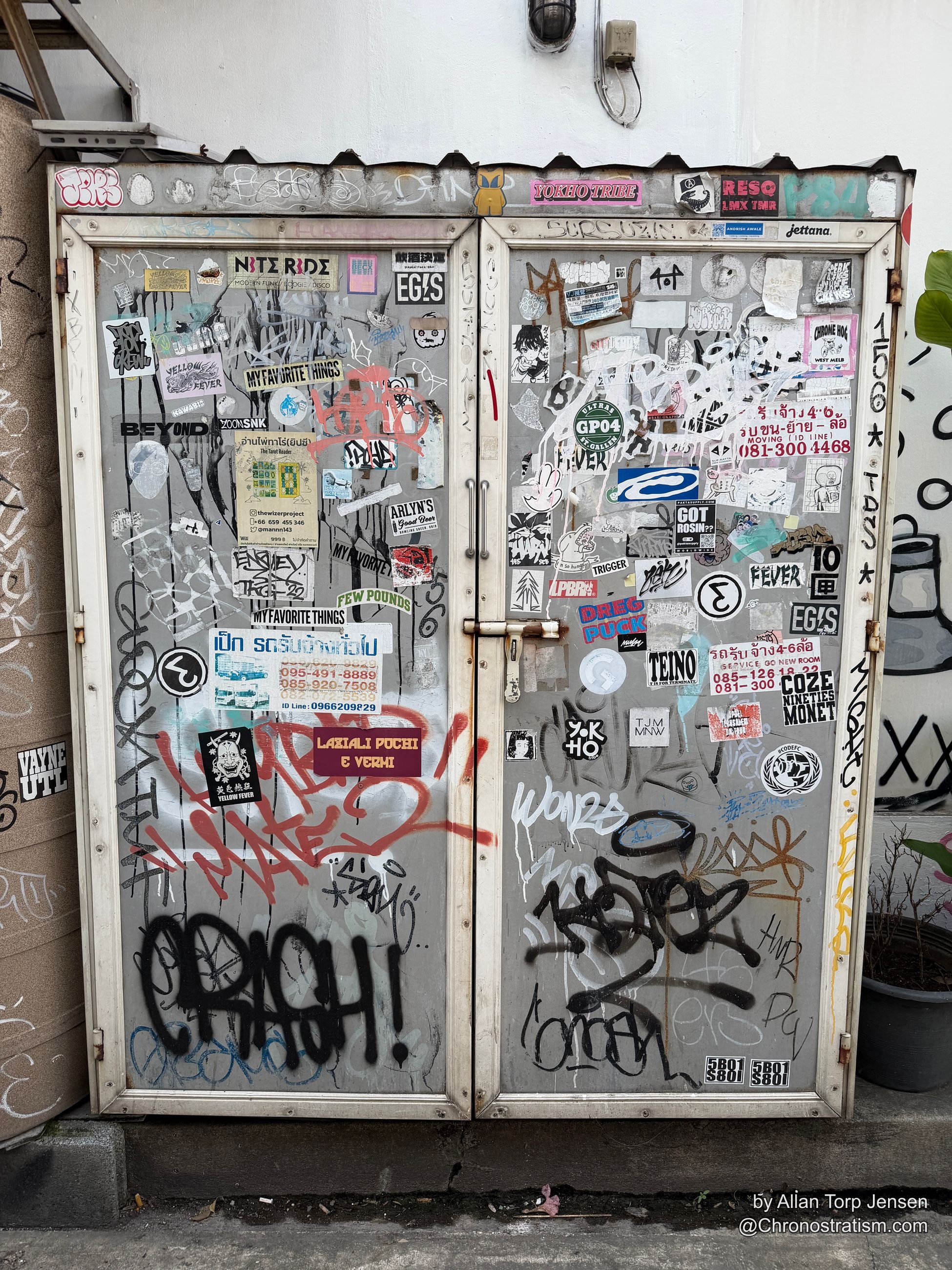 A grey utility door armoured edge to edge in overlapping stickers and crew tags.