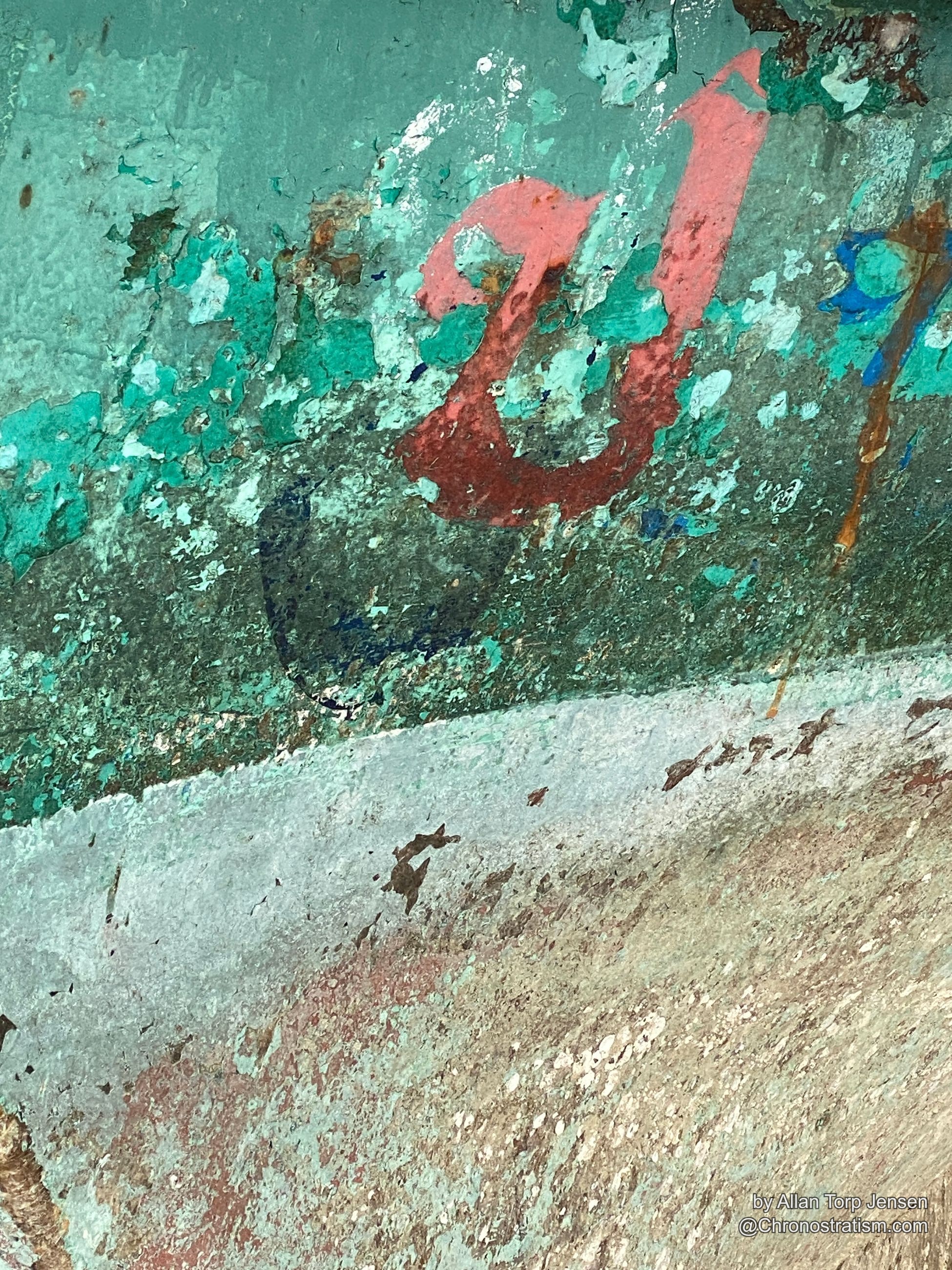 A hand-painted red arrow and number mark a heavily weathered teal-green wall.