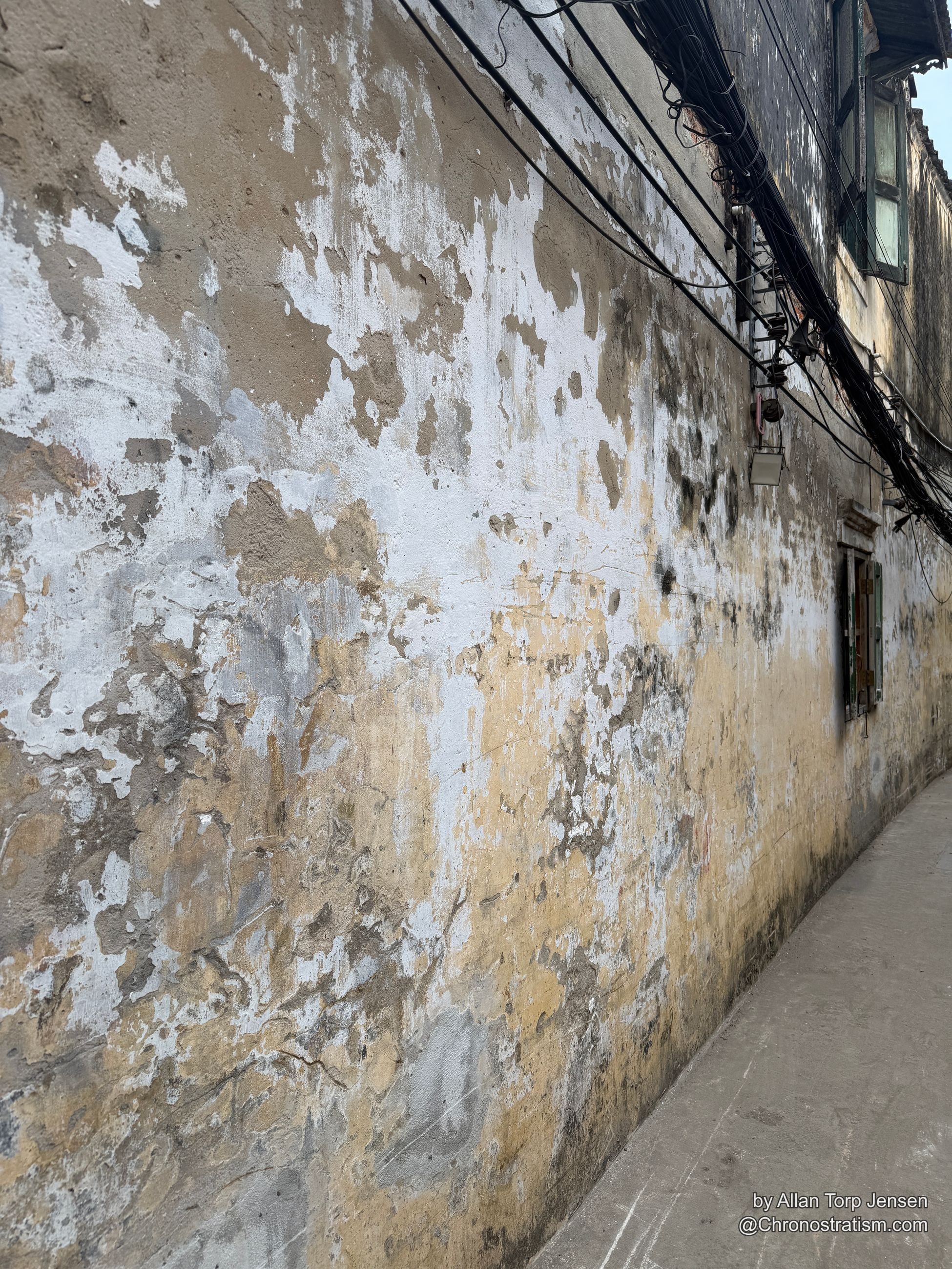 A long weathered parapet wall recedes into the distance, blotched with tan and grey water damage.