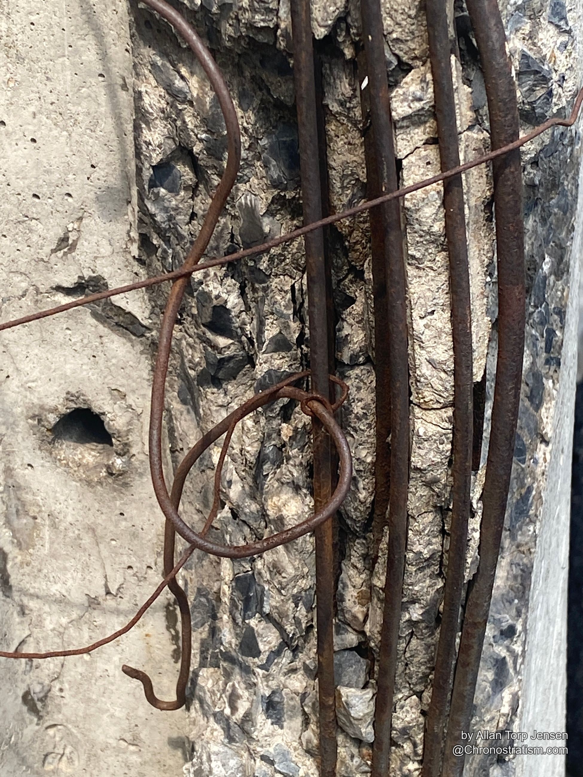 Macro detail of rust-streaked tie wire against raw concrete aggregate.