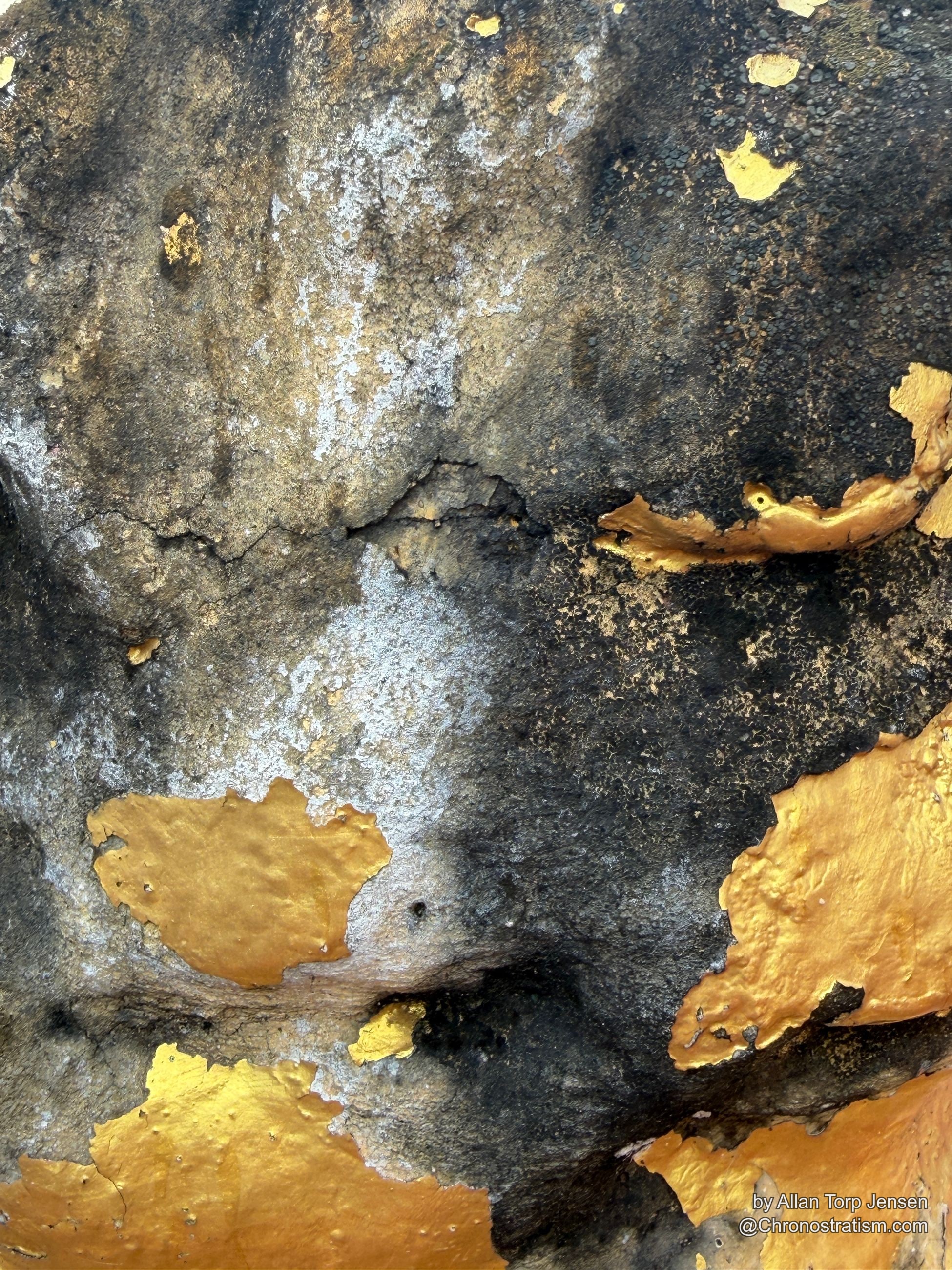 Mottled gold and black patina spreads across a weathered gilded surface.