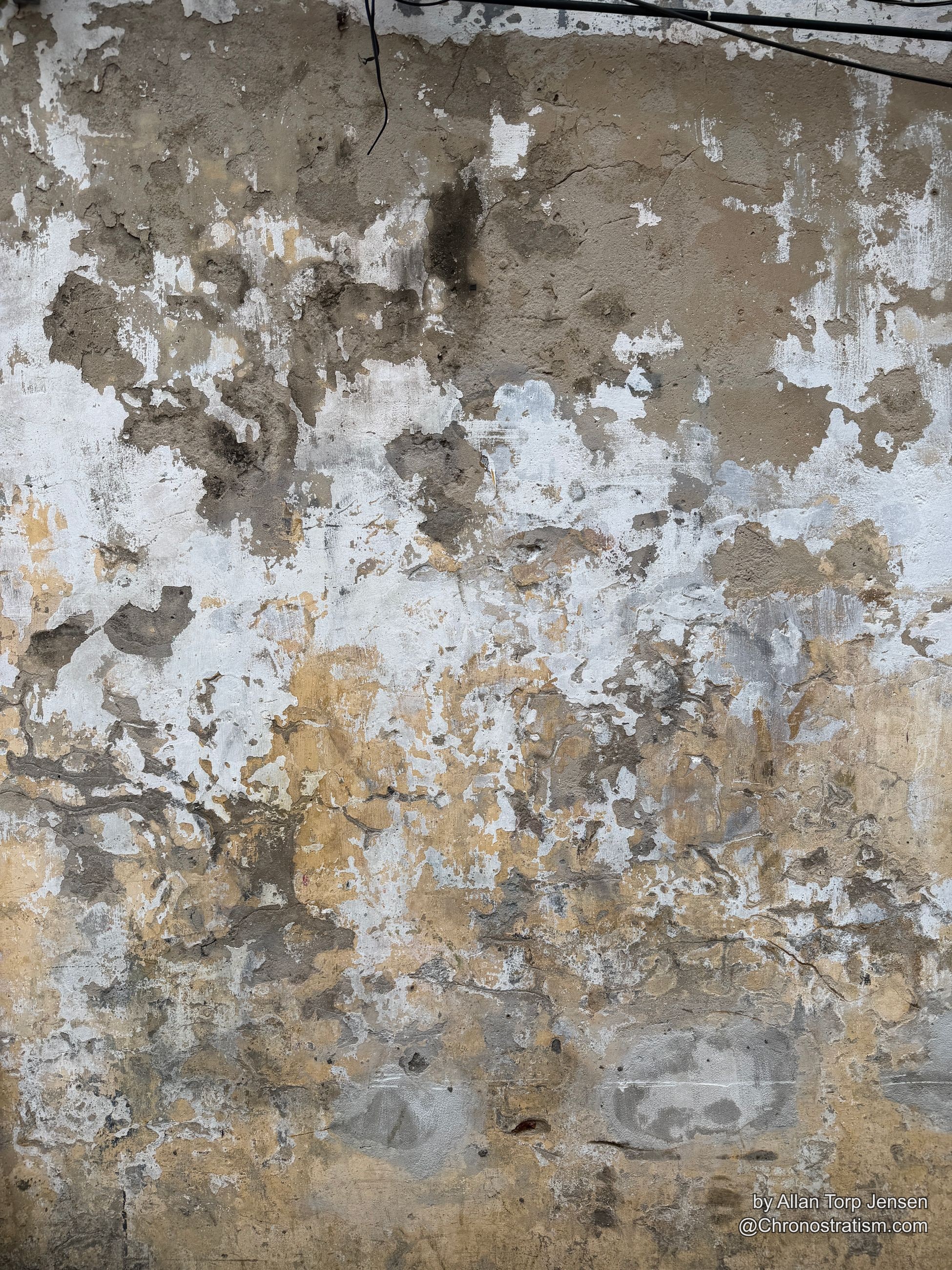 Mottled tan and grey water staining spreads across a weathered rooftop parapet wall.