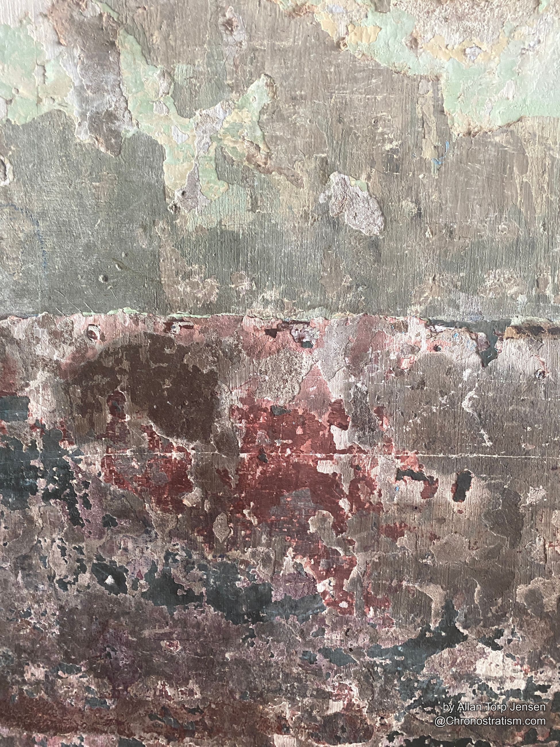 Multiple generations of peeling paint reveal olive, cream and rust-red layers beneath.