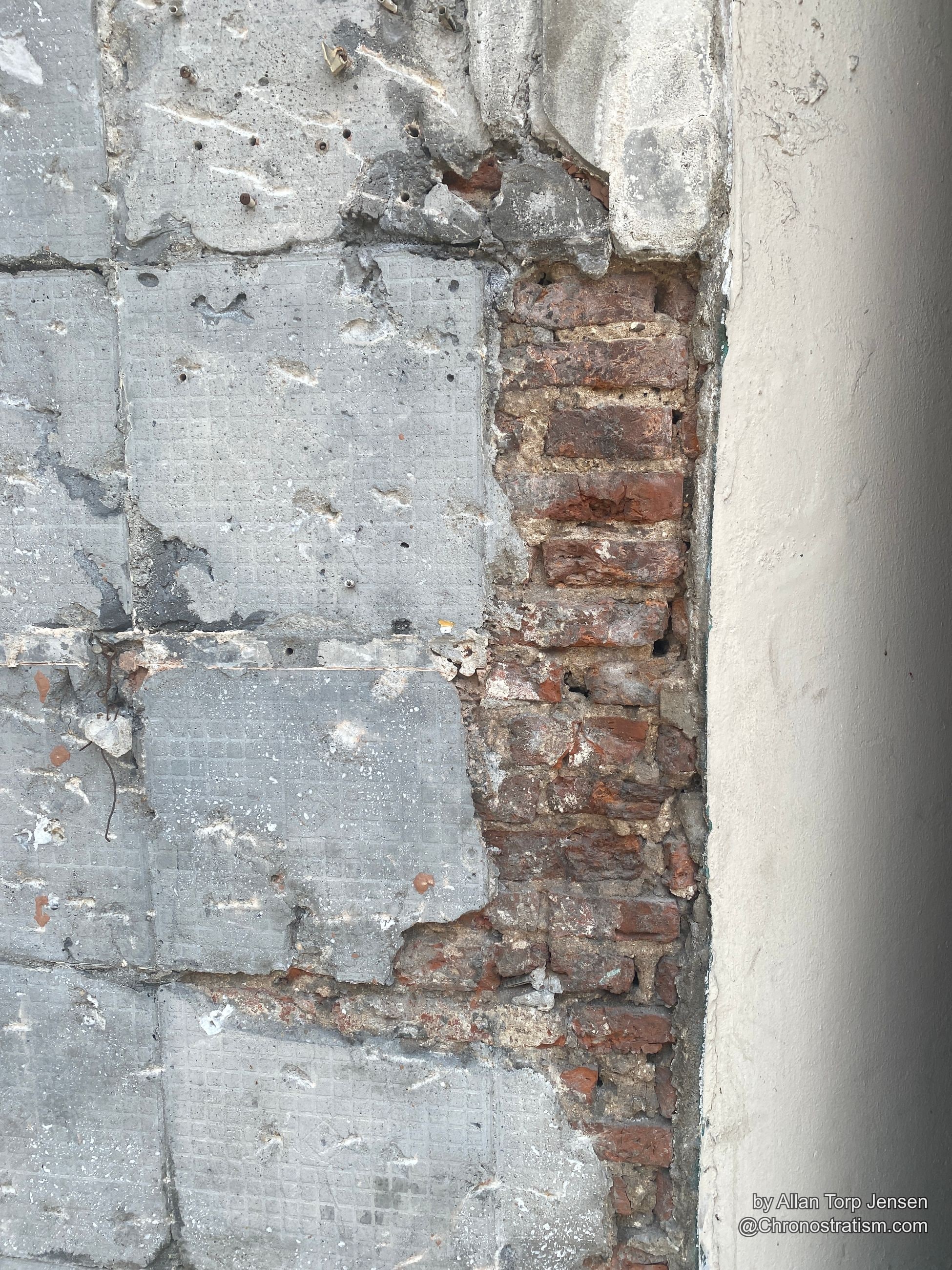 Old red brick exposed where a cement render skin has crumbled away.