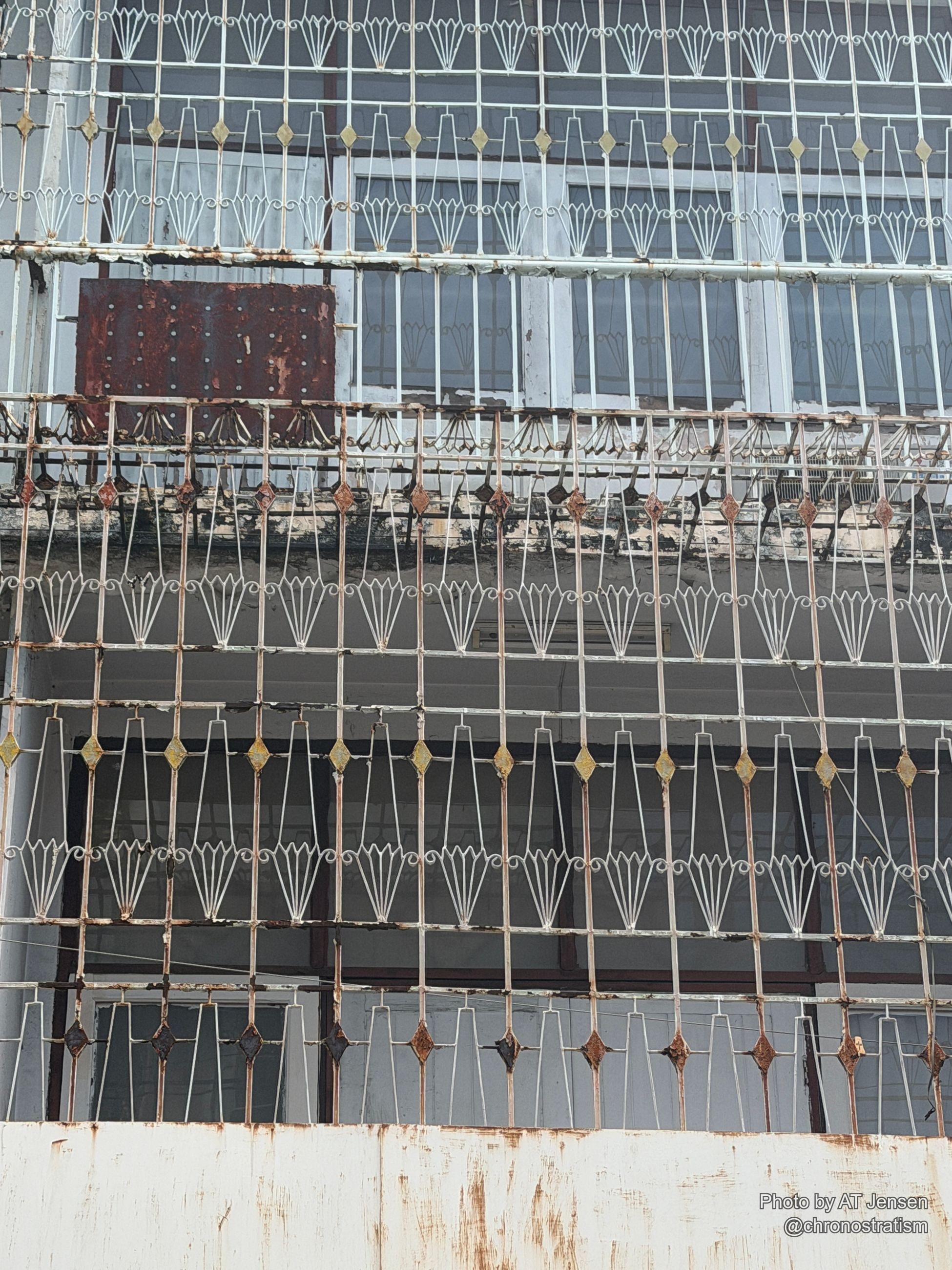 An ornate wrought-iron window grille shows rust spotting across its decorative scrollwork.