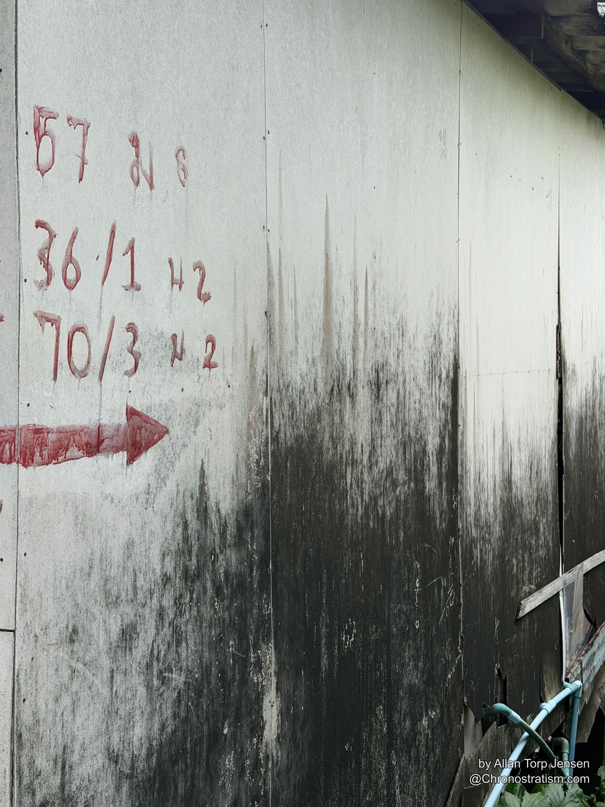 Red stencilled fractions and an arrow mark a rooftop membrane, a dark water-stain gradient spreading across it.
