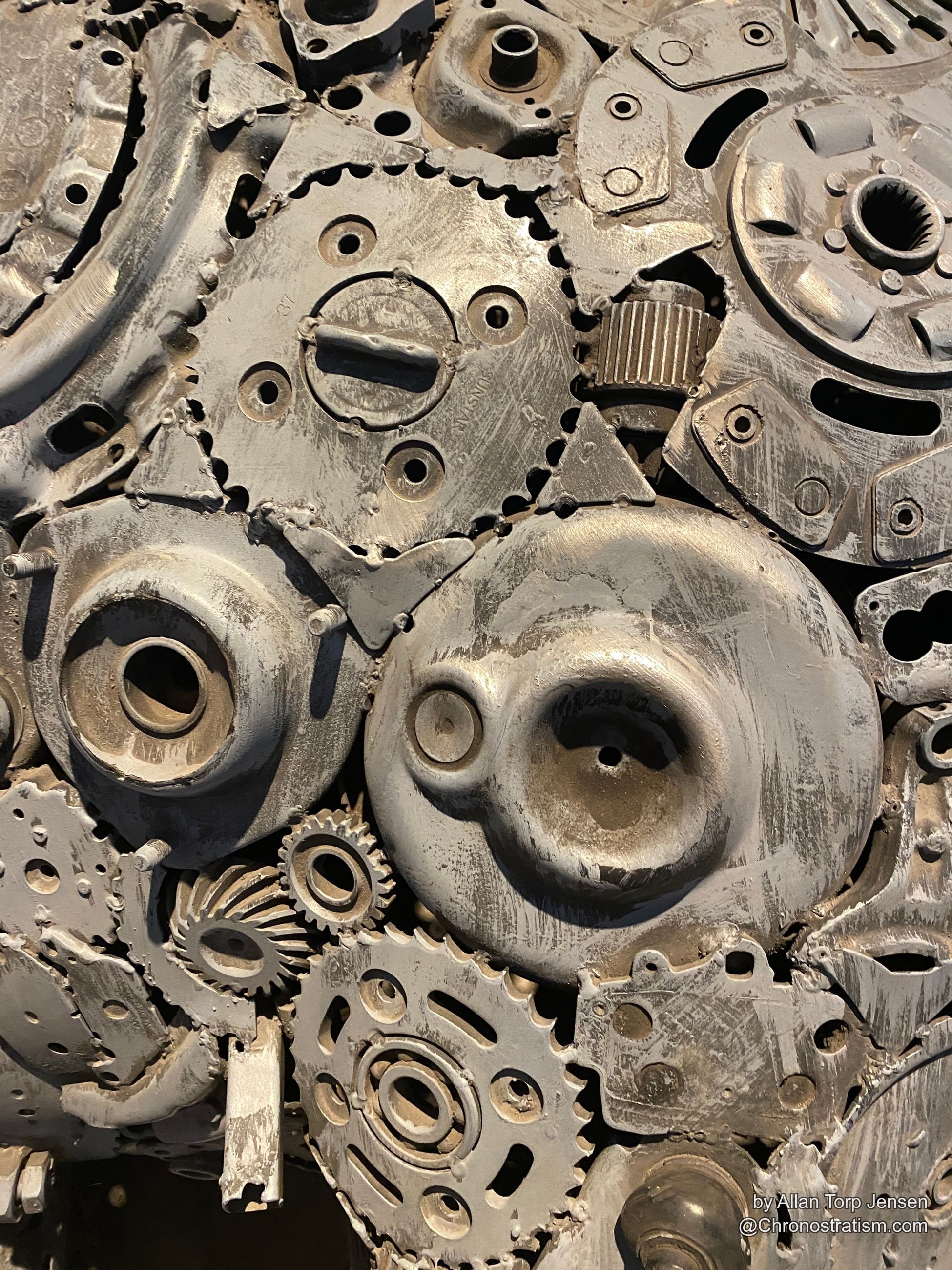 Silver-toned worn machine parts and cogs, embossed lettering visible.