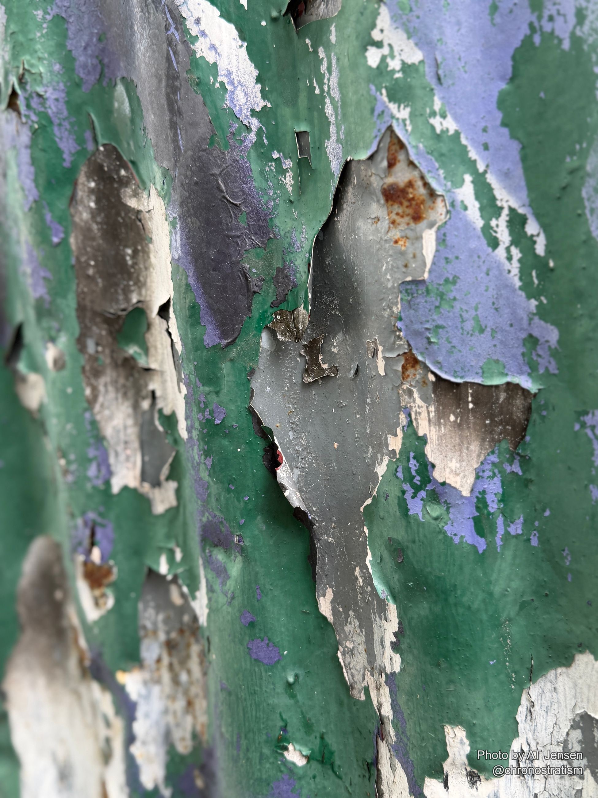 A small rust spot punctuates the peeling purple and green paint.