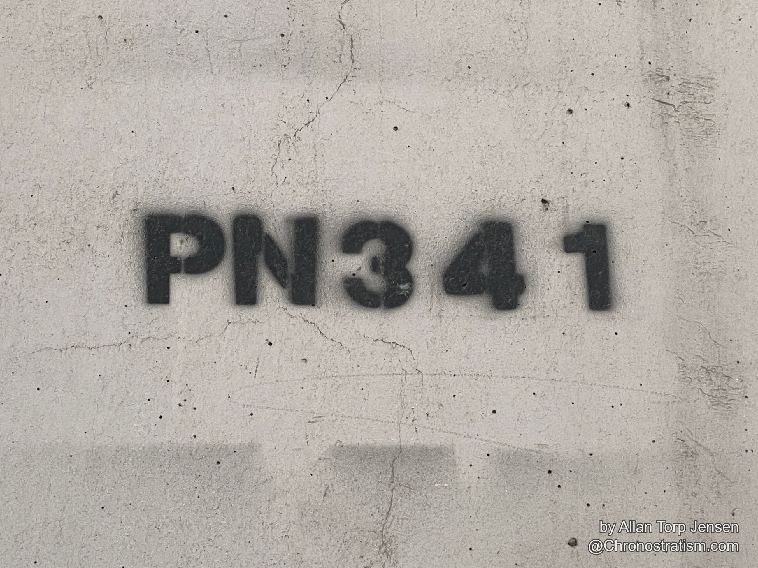 A spray-stencilled alphanumeric code marks a cracked grey render wall.