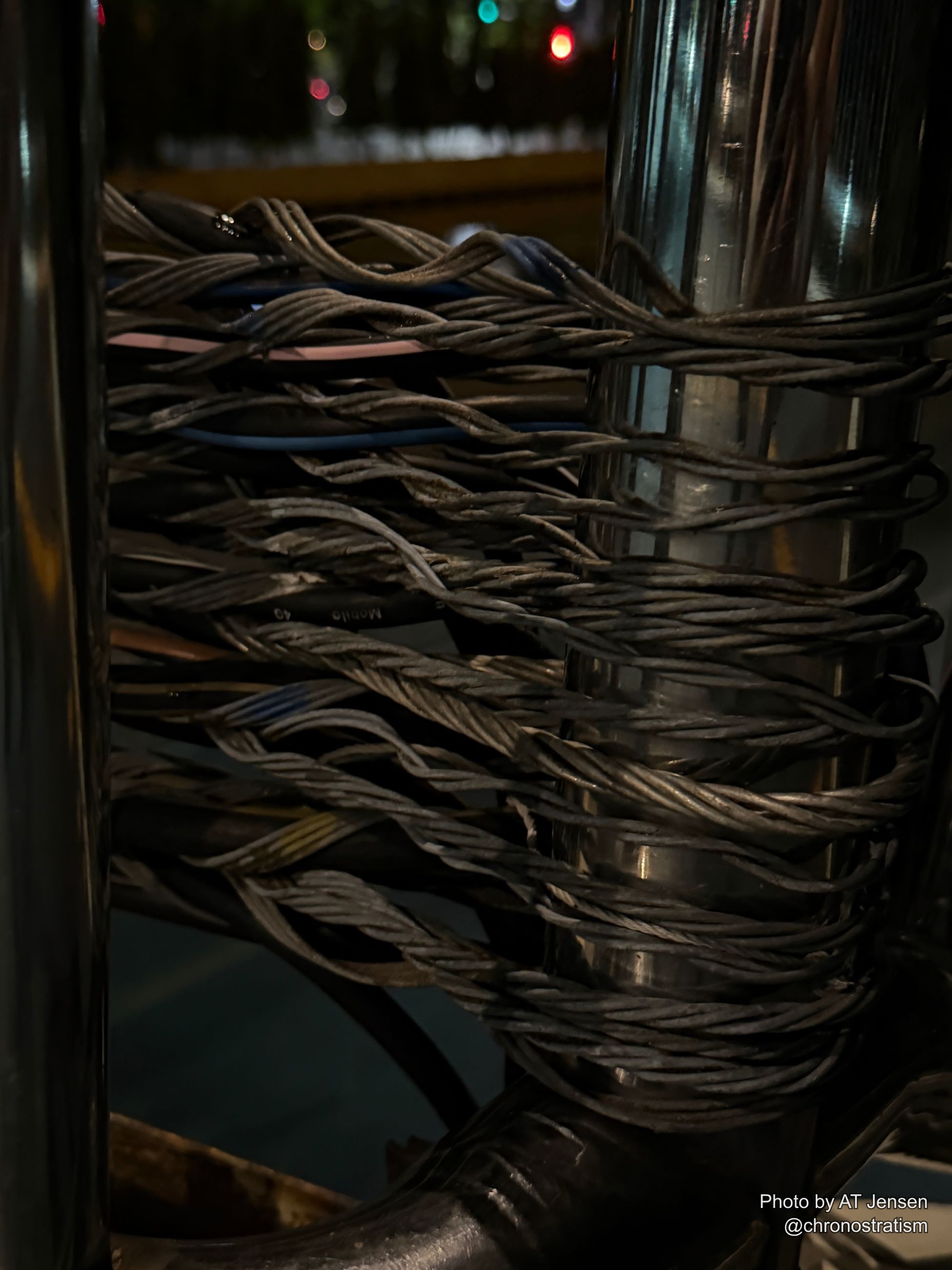 A stencilled marker sits beside a knot of aging telecom cable.