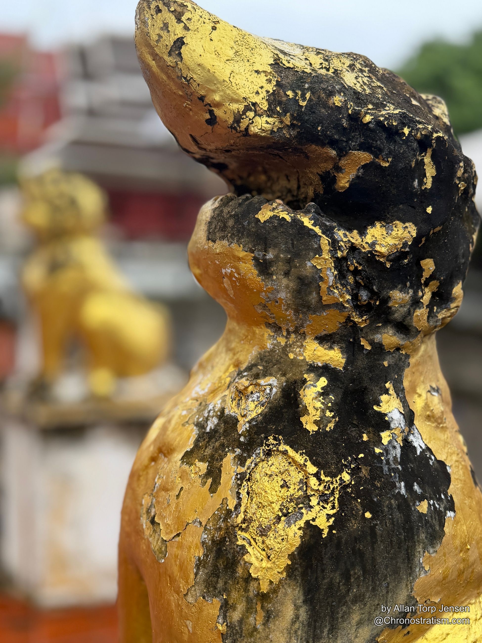 Swirling gold and black patina texture across the statue’s gilded body.