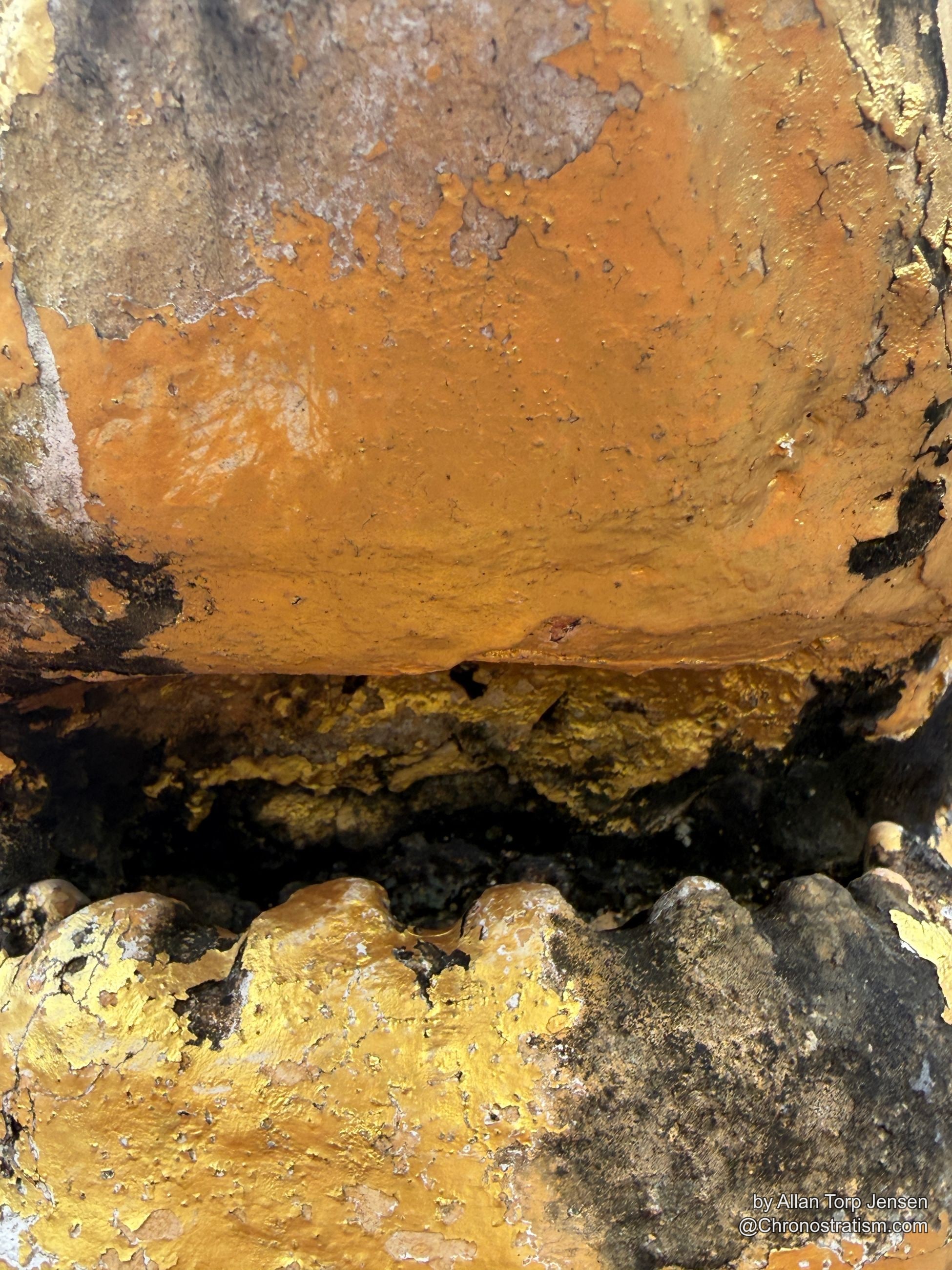 A vertical seam in the gilded surface collects dense black soot residue.